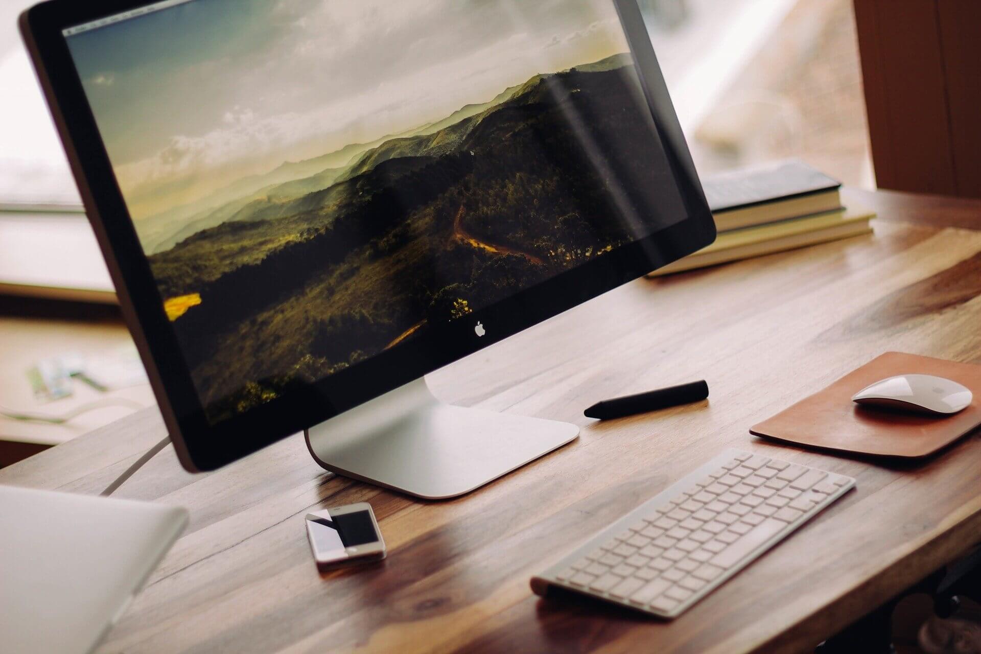 Agenturpartner von eRecht24 iMac auf einem Schreibtisch mit Büchern, Tastatur und Maus