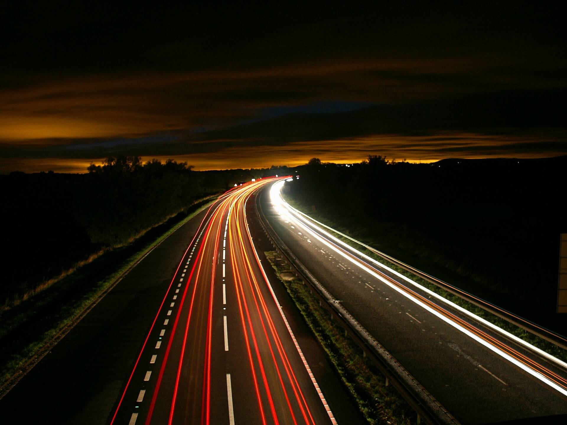 Mehr Traffic benötigt mehr DDoS-Schutz Autos auf einer Autobahn bei Nacht, durch Langzeitbelichtung sind nur rote und weiße Streifen sichtbar