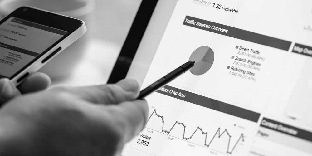 Managed Services Eine Person, die in der Hand einen Stift hat und auf ein Tablett mit Graphen zeigt